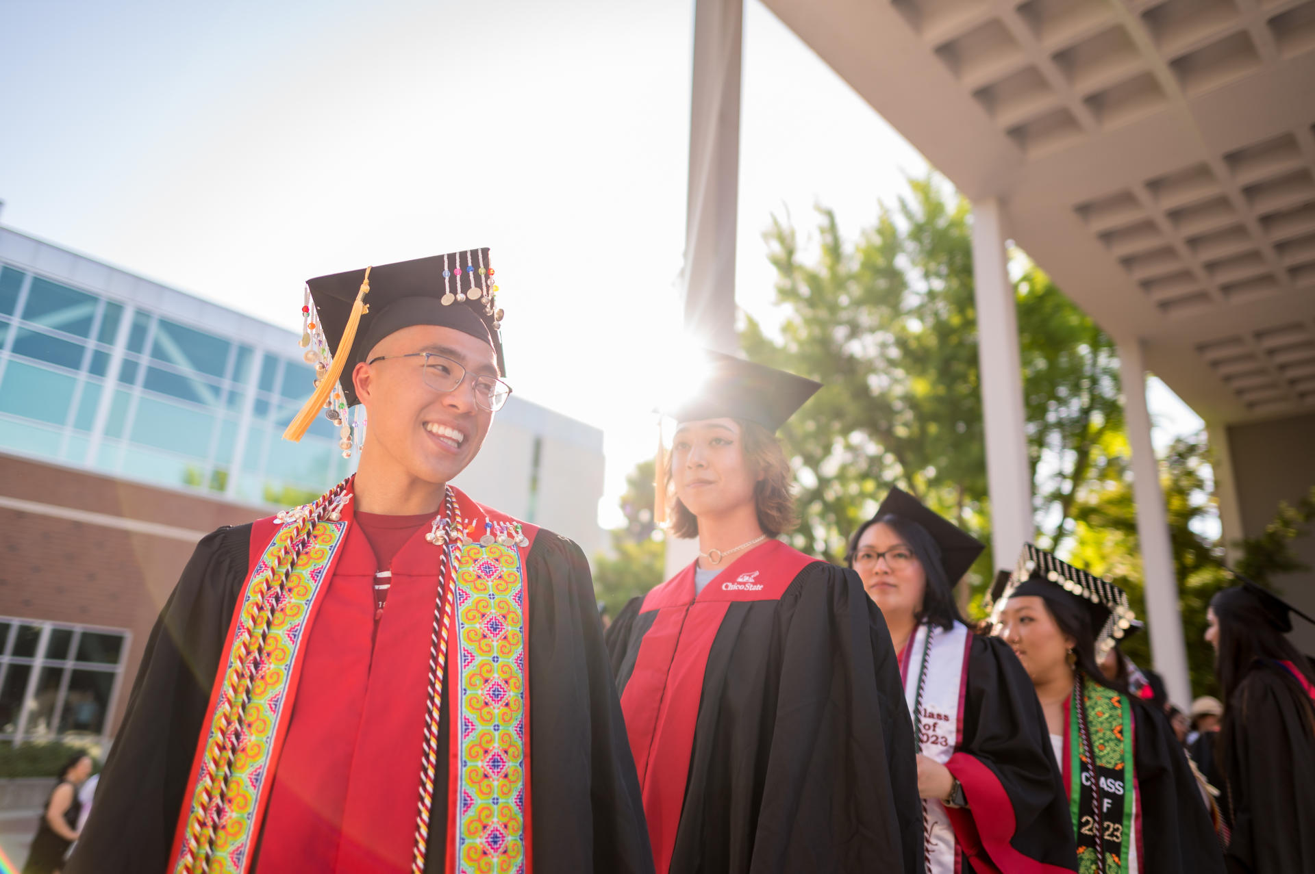 Graduates smile in their caps and gowns.