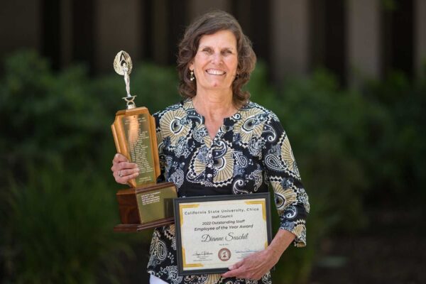 2022 Employee of the Year honoree Dianne Suschil holds up her trophy and certificate after being honored at a ceremony on campus.