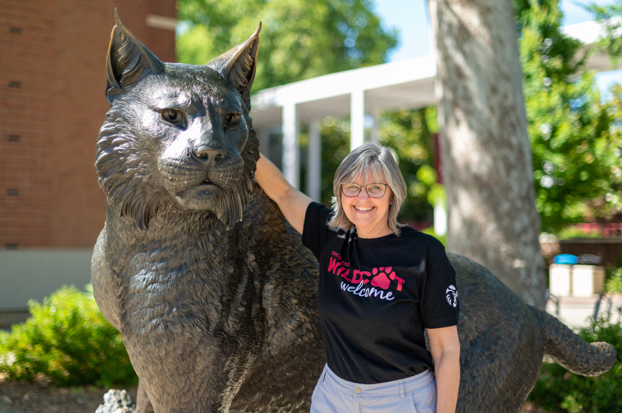 Rosemary White stands with an arm around the Wildcat Statue in Wildcat Plaza
