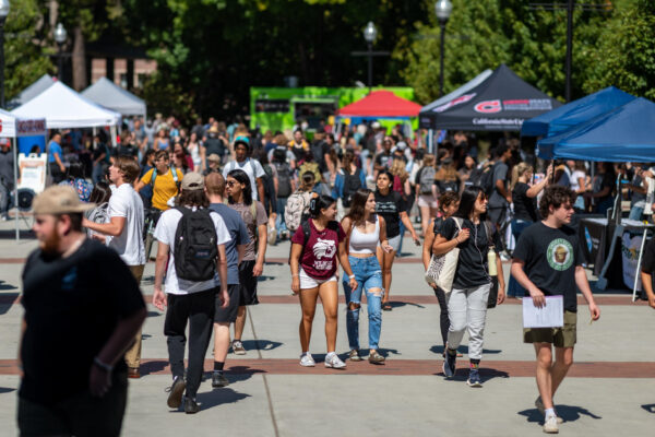 A crowd of students walk down the sidewalk at Chico State