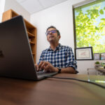 Abbas Attarwala, who was awarded a $30,000 grant this summer to research the impacts of AI on children, is photographed at his desk while he is typing on a laptop.