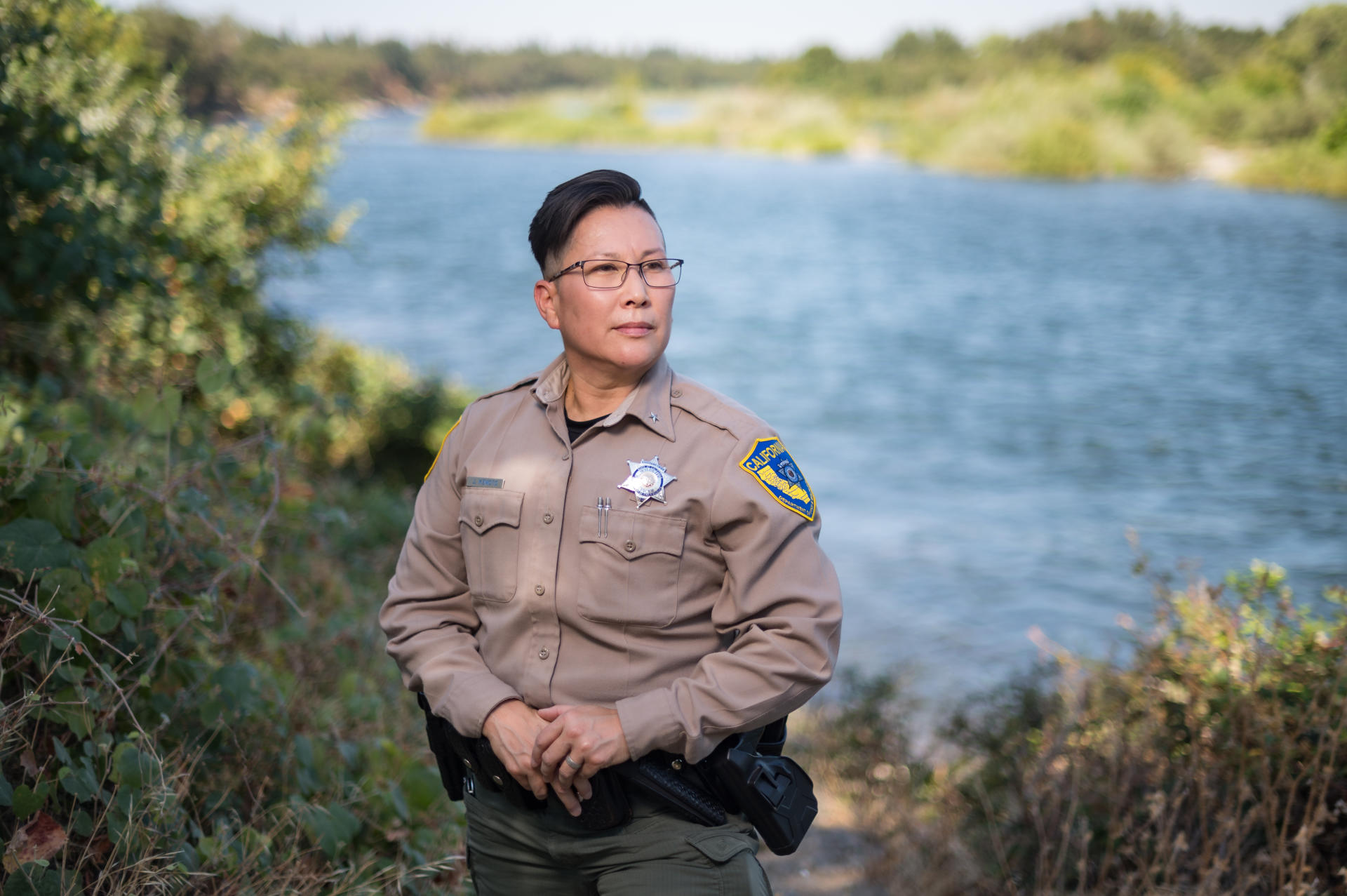 Jennifer Ikemoto, assistant chief of special operations for California Department, poses for a photo while wearing her uniform and stands along the American River near the DFW Regional Office in Rancho Cordova, Calif.