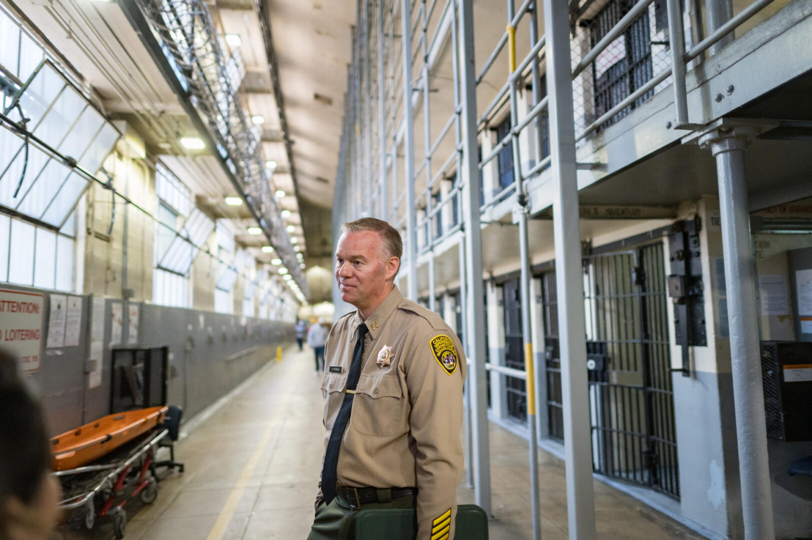 Capt. Keith Michels stands in a hallway of one of the housing units at Folsom State Prison. Prison cells can be seen in the background. 