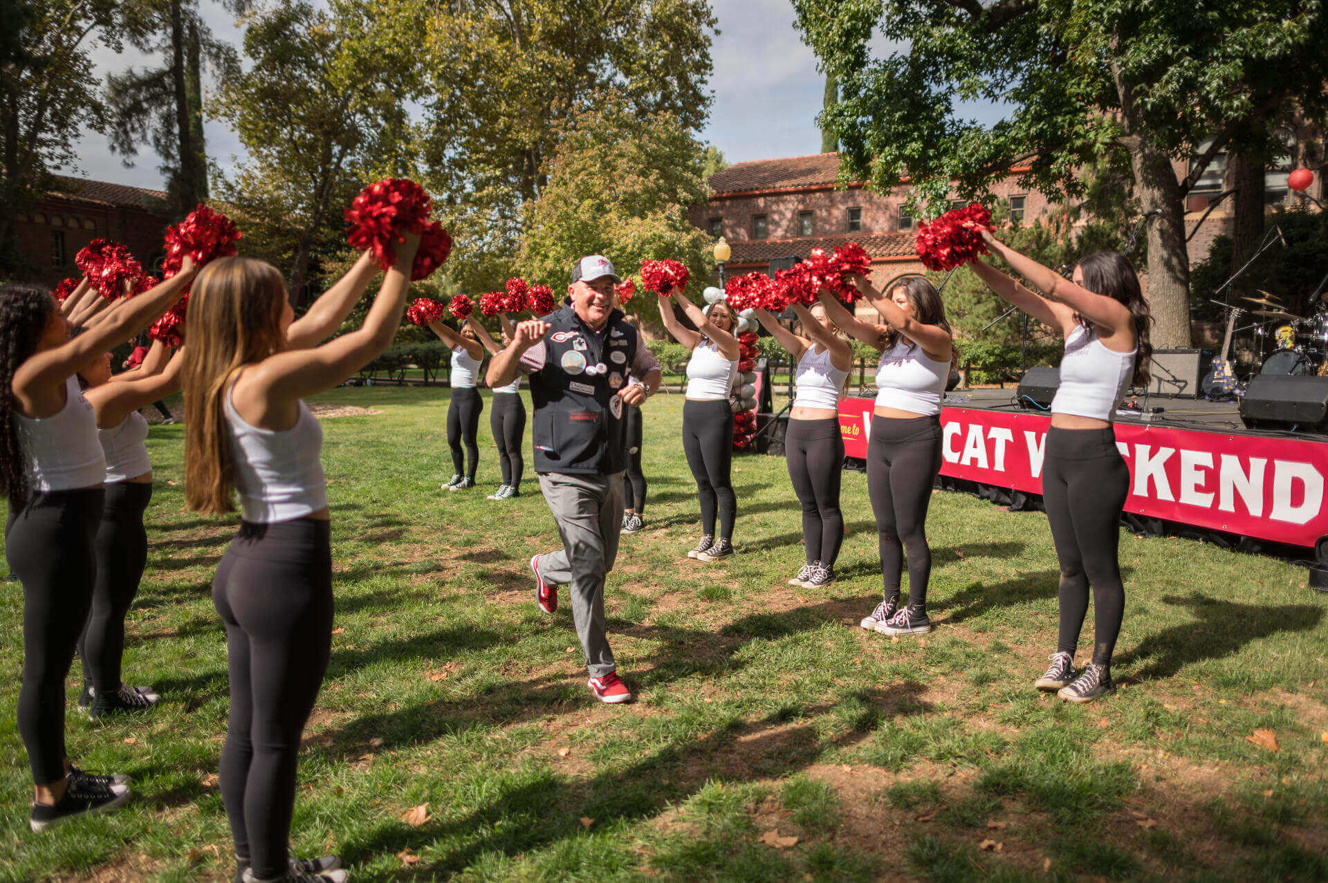 President Steve Perez runs through Expressions Dance team with raised pom poms as the campus community enjoys the Alumni and Family Weekend BBQ barbecue as part of Wildcat Weekend