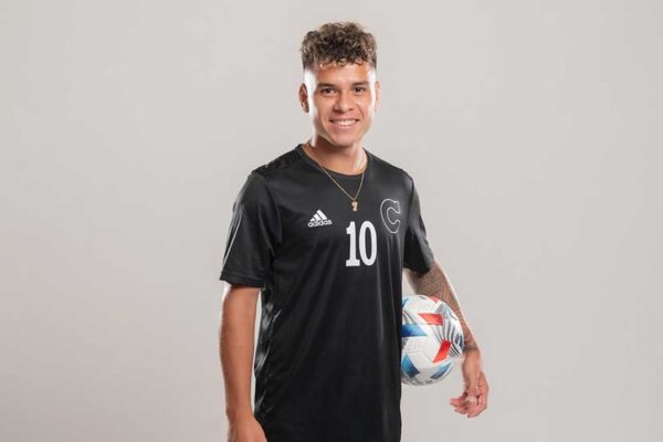 Adrian Fontanelli poses for a portrait with a soccer ball between his left arm and hip.