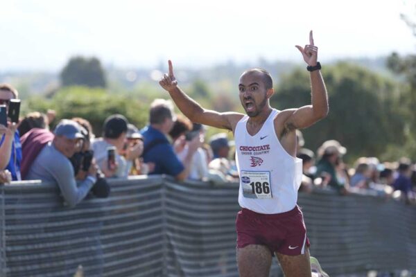 Chico State cross country student-athlete Dylan White raises his hands in triumph as he crosses the finish line as the 2023 CCAA individual champion