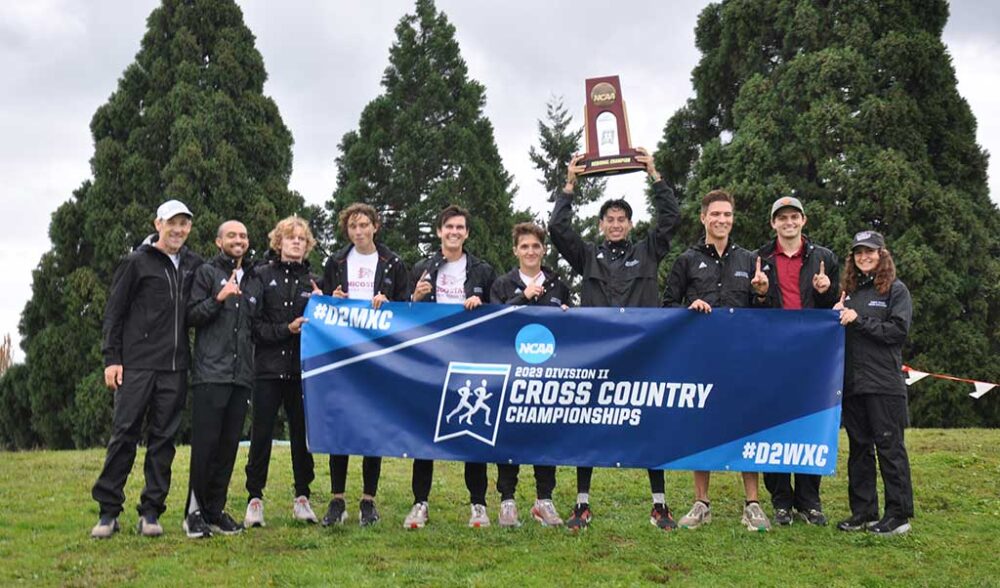 Members of the 2023 Chico State men's cross country team hold up the Division II Cross Country Championship banner and West Region championship trophy.