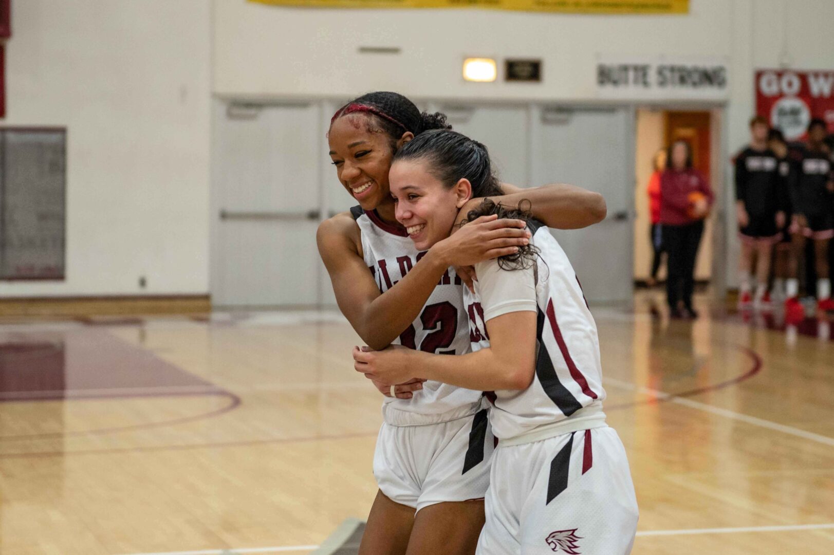 Wildcats Zhane Duckett (left) and Brandy Huffhines embrace after winning their basketball game.