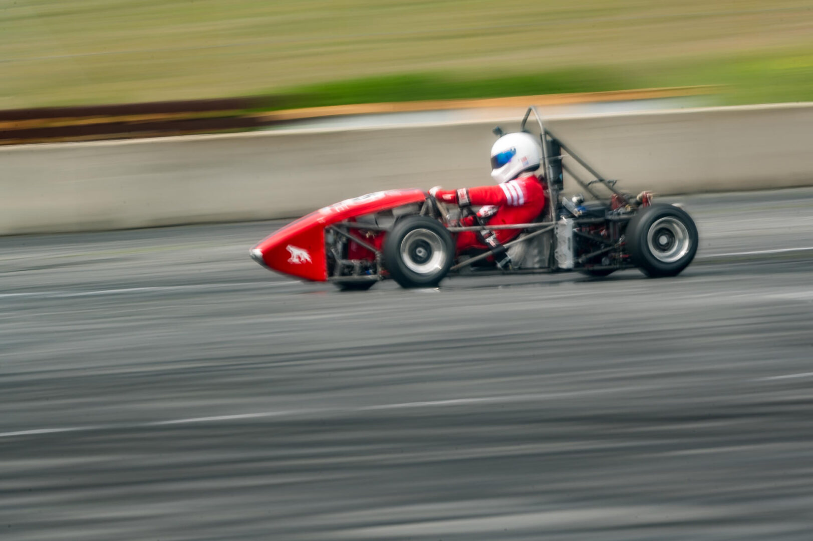 Andre Fatehi is photographed while he test drives a red Formula SAE vehicle at Thunderhill Raceway.