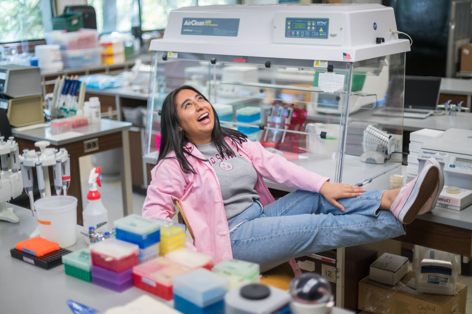 Donning her pink lab coat and pink shoes, Nayellie Barragan-Mejia sits back on a chair with her feet up on a desk as she laughs.