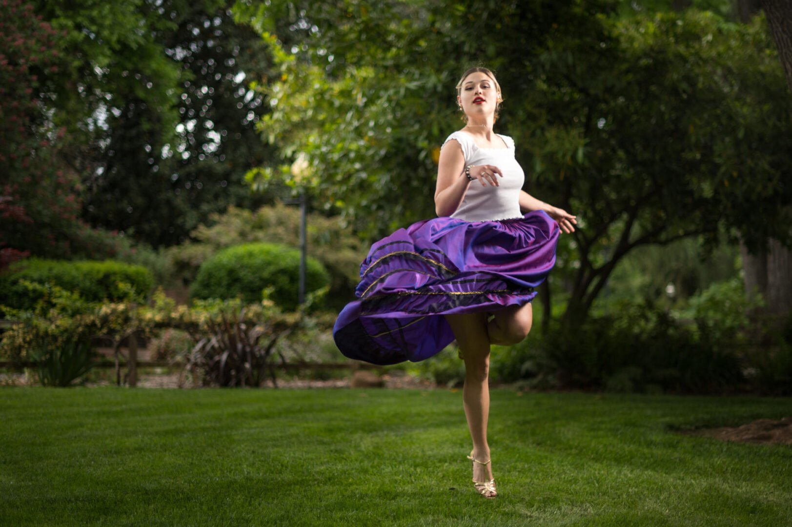 Dancer Susana Correa-Avila Robb wears a white top and purple skirts as she performs and poses on campus.