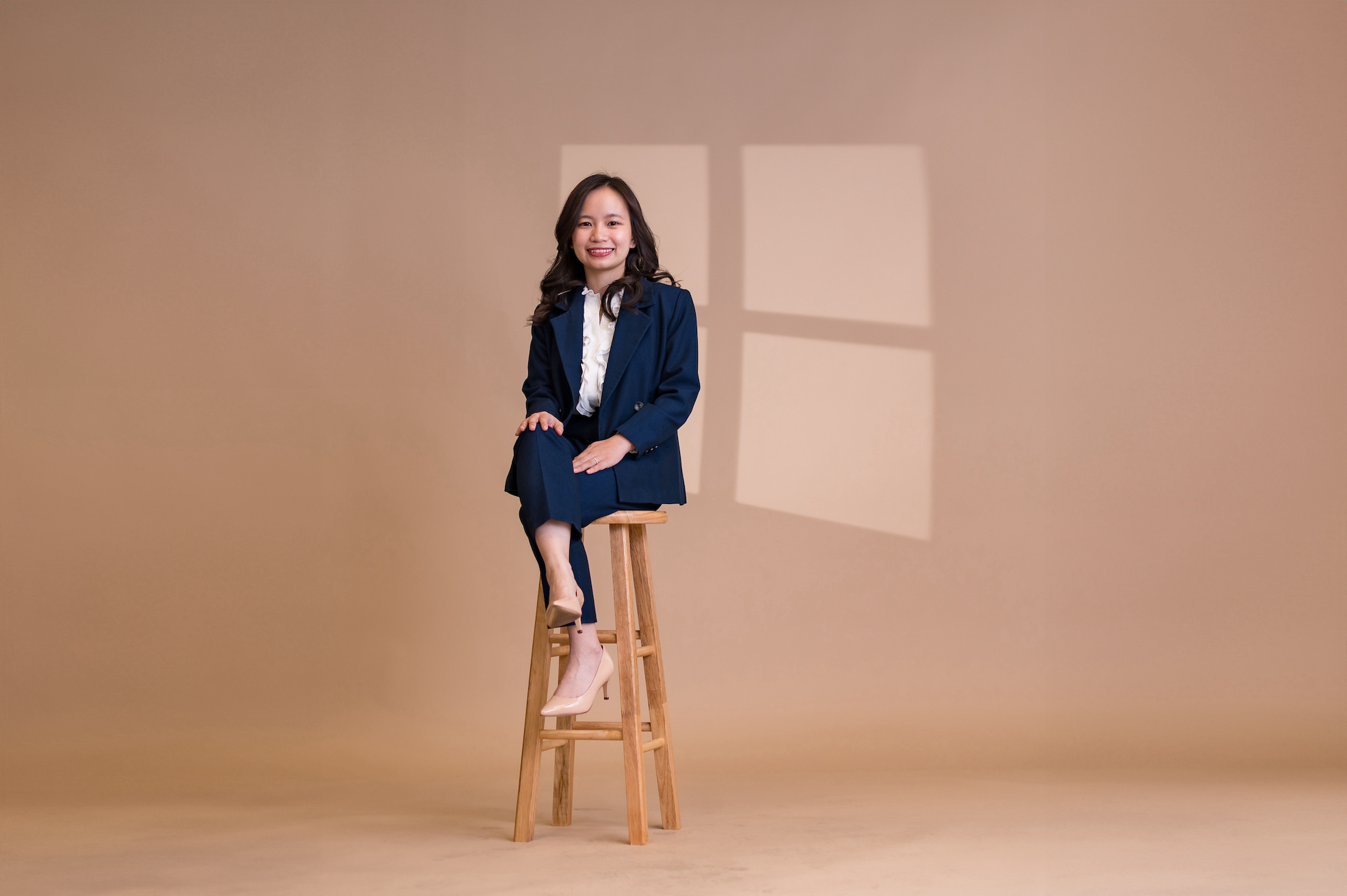 Emma Pham poses on a stool in a blue business suit.