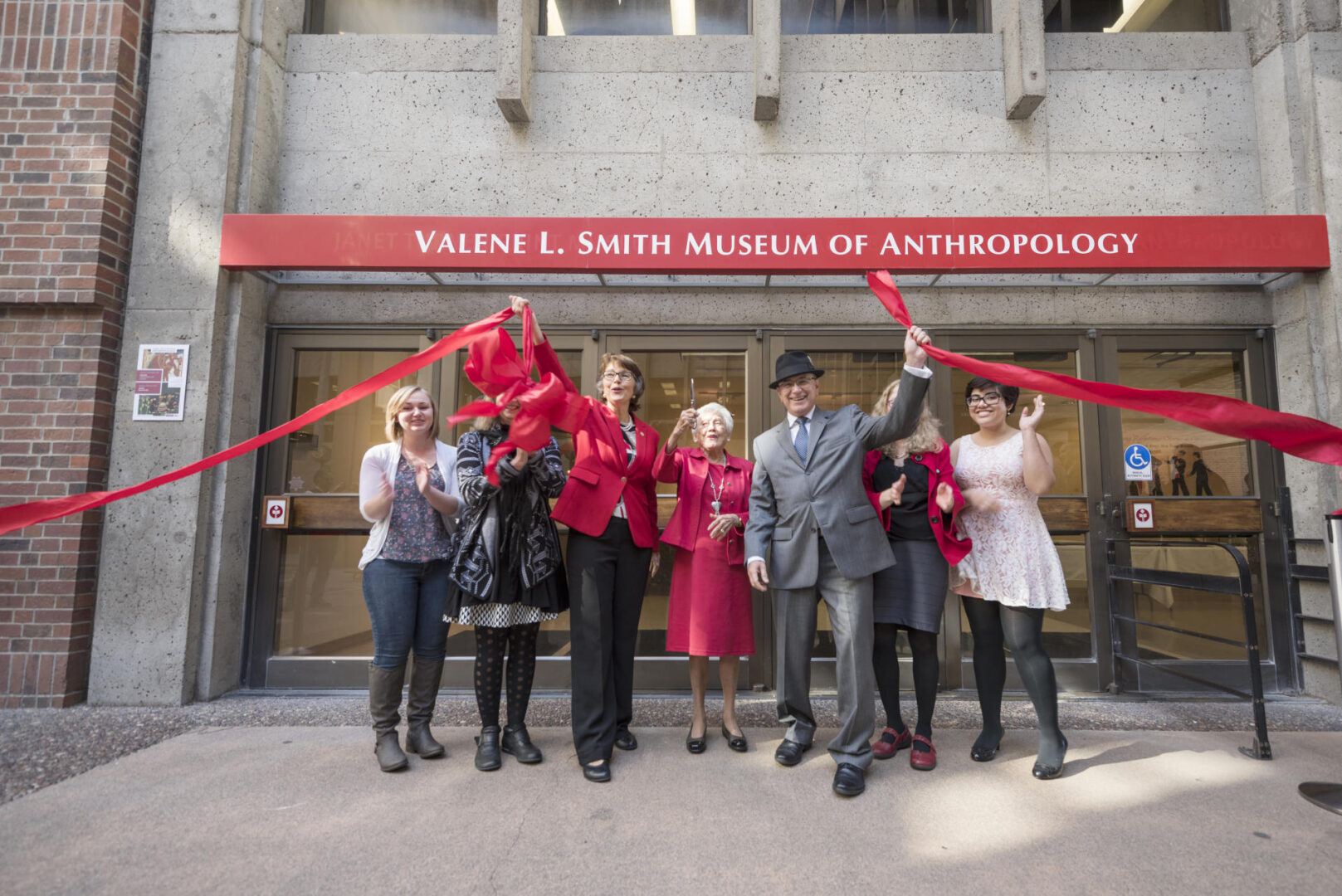 Valene Smith stands in a row of celebratory people as they cut the giant ribbon to open the new Valene L Smith Museum.