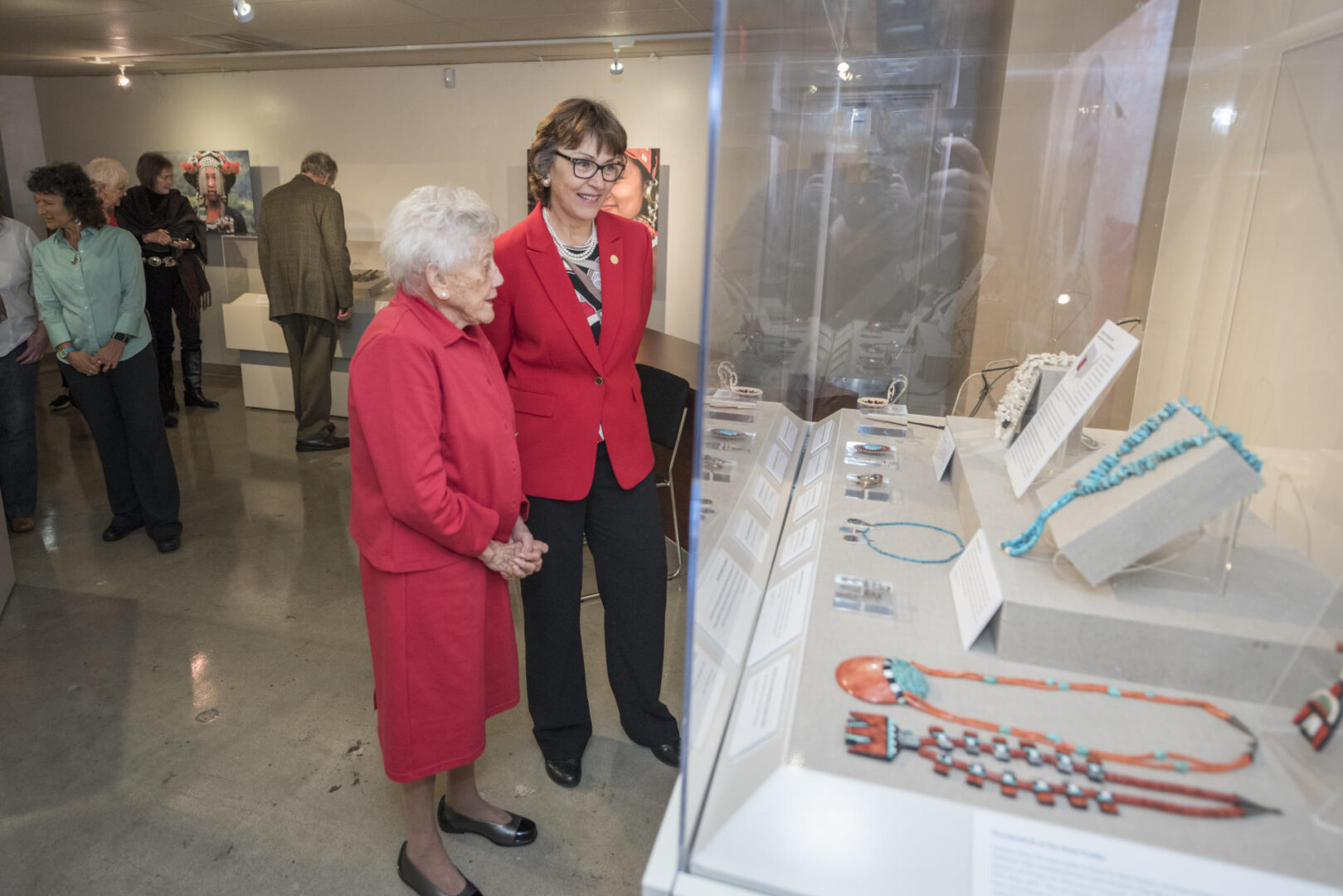 President Gayle Hutchinson and Valene L Smith admire jewelry in glass cases at the musuem.