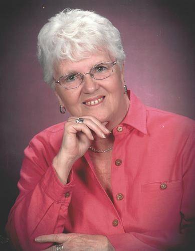 A portrait of Doris Mann smiling in a pink shirt.