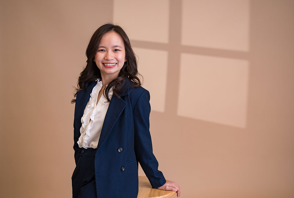 Nhung Pham poses on a stool in a blue business suit.