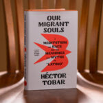 A hardcopy of Our Migrant Souls sits on a chair in dramatic lighting.