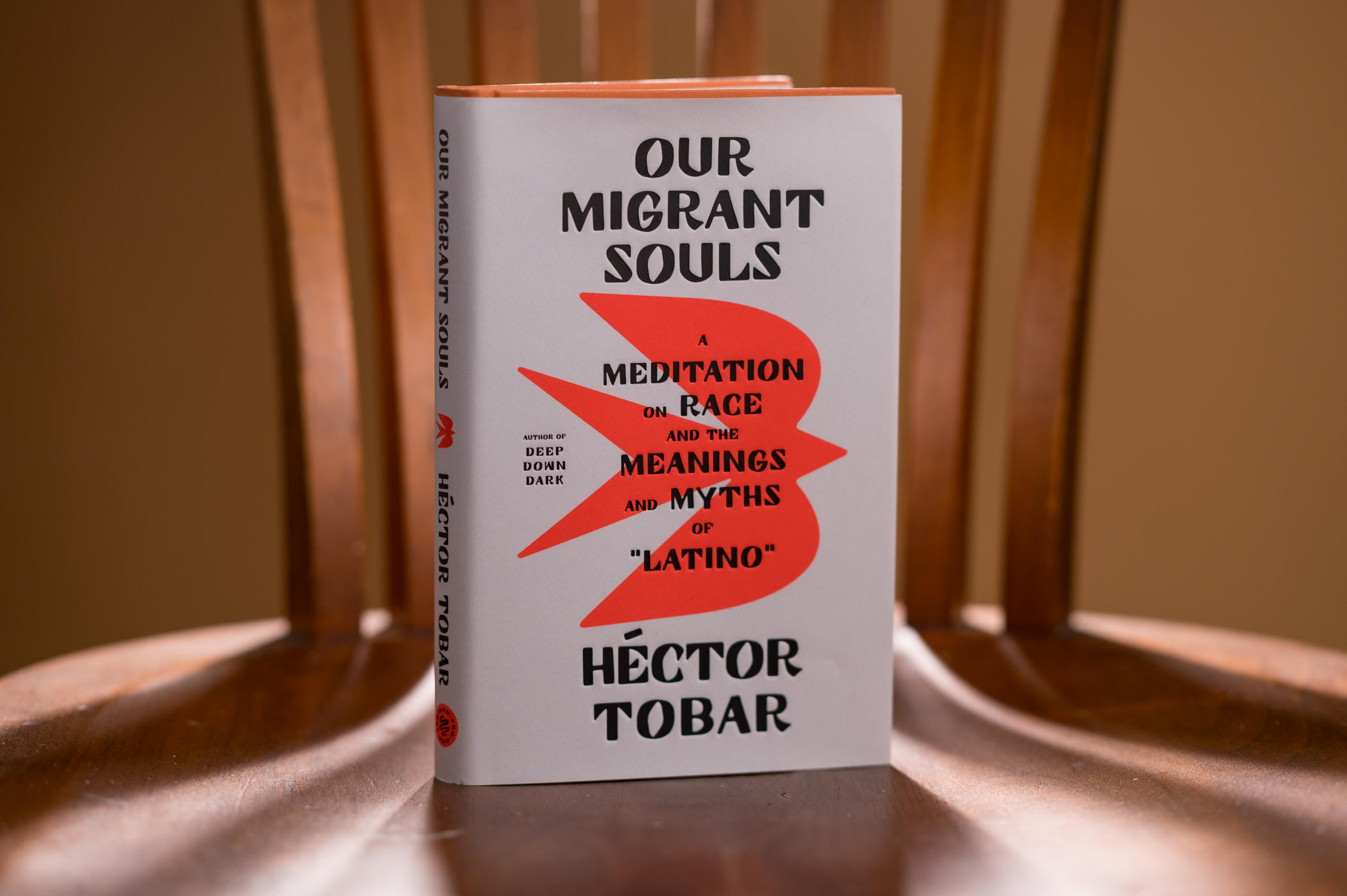 A hardcopy of Our Migrant Souls sits on a chair in dramatic lighting.