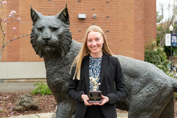 Kristen Chatham stands in front of the Wildcat statue holding a trophy