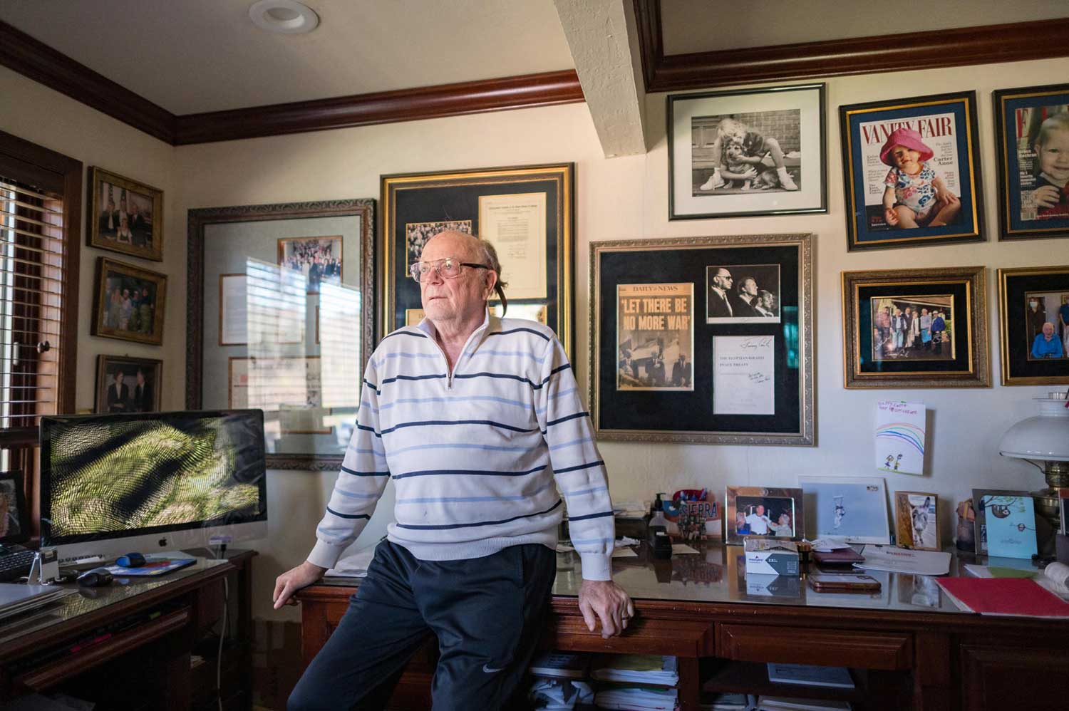 Dan Ostrander in his home office, surrounded by framed newspaper clippings and photos.
