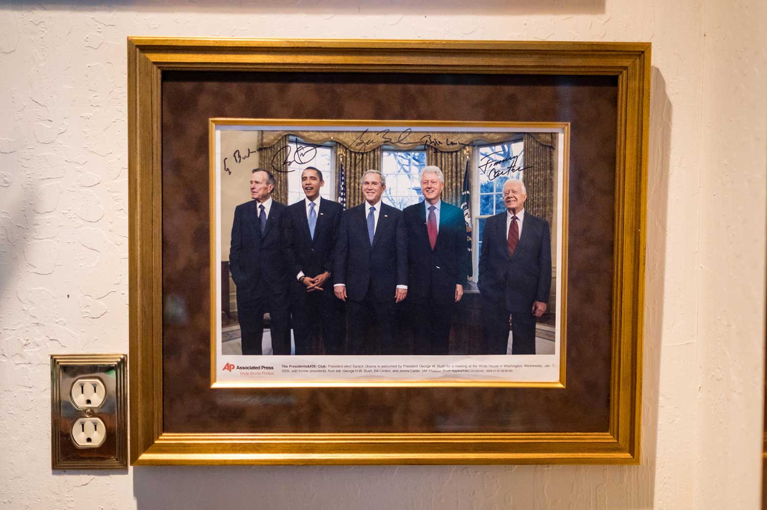 A framed photo of President Barack Obama being welcomed to the White House by President George W. Bush and joined by former presidents George H.W. Bush, Bill Clinton, and Jimmy Carter. The photo is autographed by all five men.