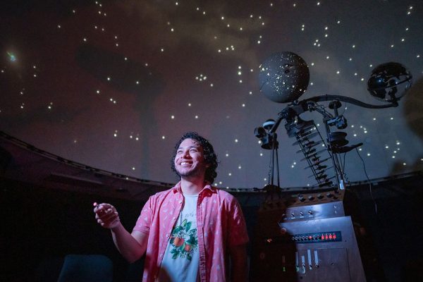 Giovanni Paz-Silva looks up at the ceiling inside Chico State's planetarium, using a laser pointer to identify a star.