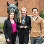 From left to right, Natalie Bourn, Kristen Chatham, and Finn Blacker pose in front of a Wildcat statue. Chatham holds a small trophy in her hand.