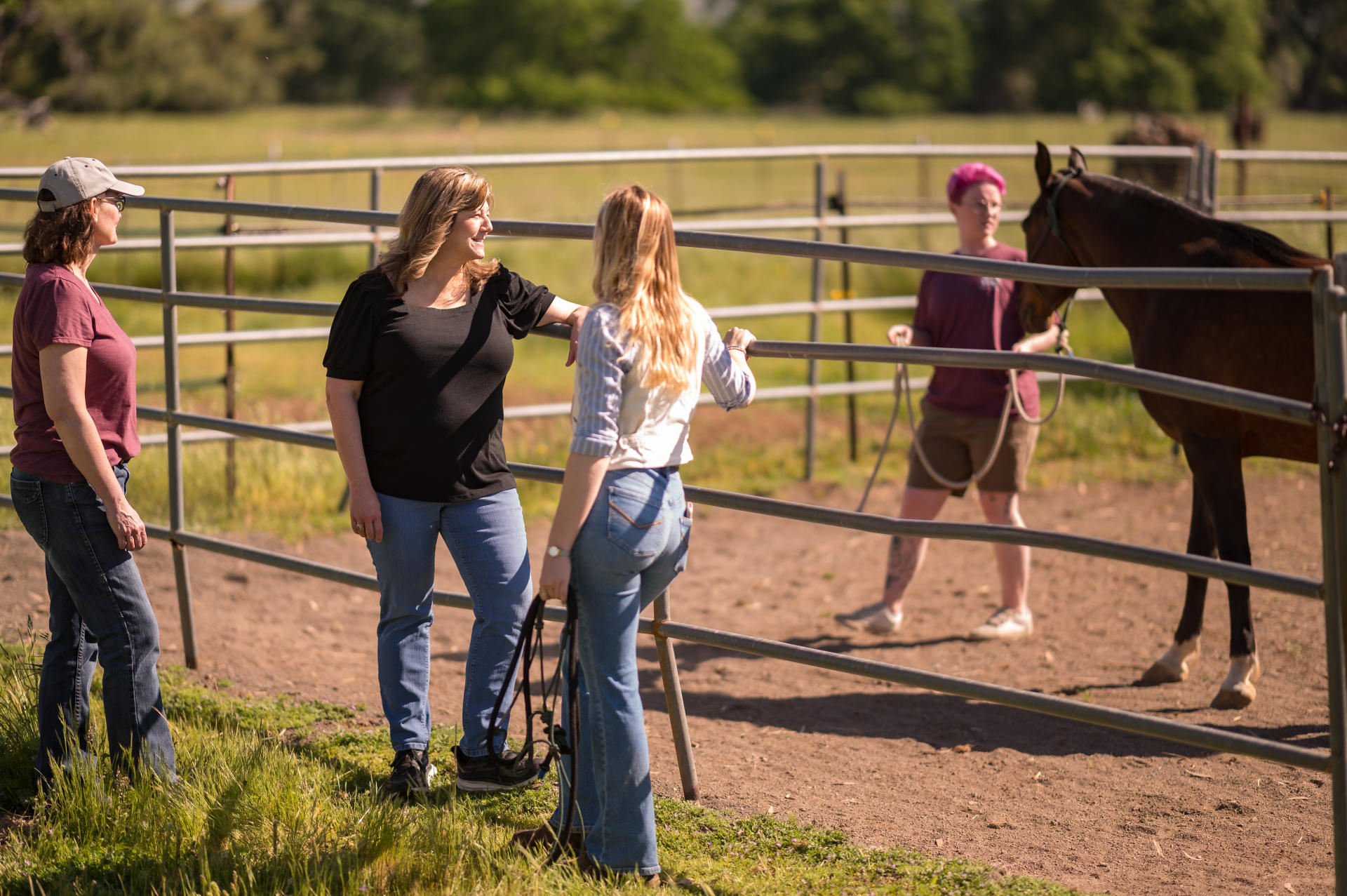 Three people stand and talk outside a horse arena .