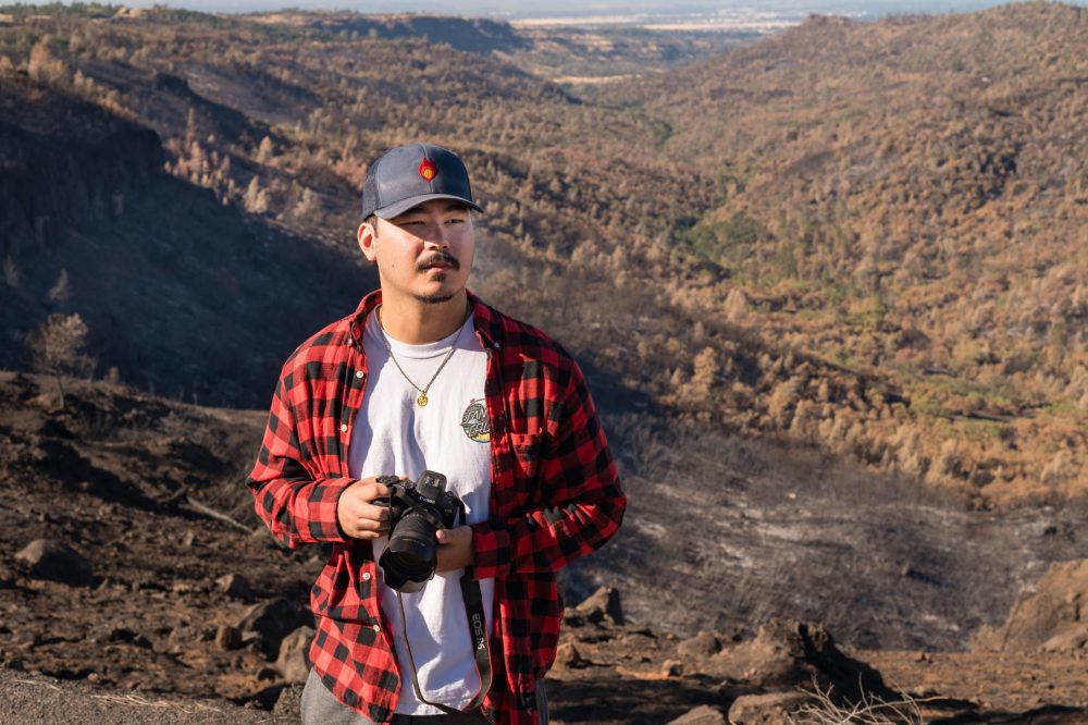 A student poses with camera in hand, with the Big Chico Creek watershed fanning out behind him.