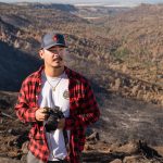 A student poses with camera in hand, with the Big Chico Creek watershed fanning out behind him.