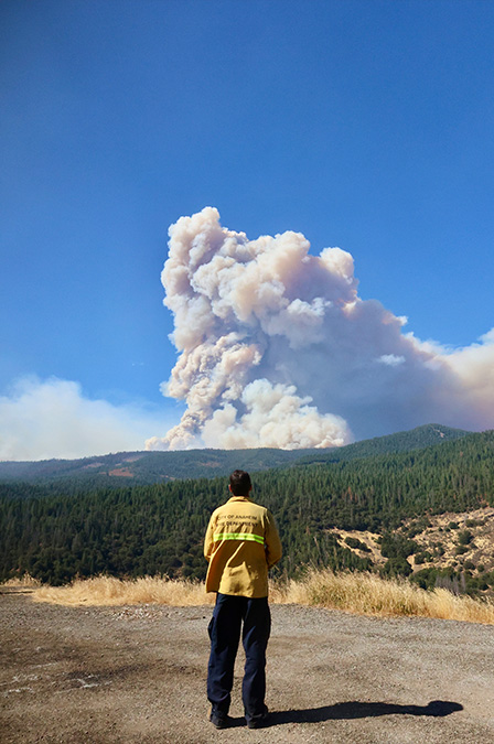 Fireline paramedic Jason Hibbard watches plumes rise over the treeline during the Park Fire.