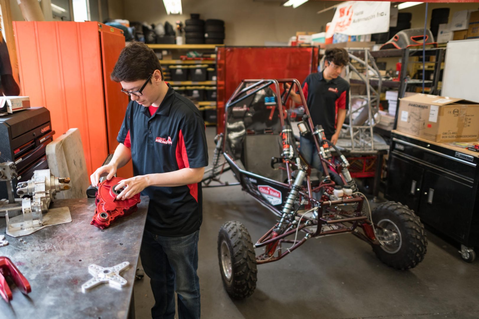 Two students work on an off-road racecar in a mechanical engineering labratory.