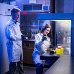 Assistant Professor Logan Smith (left) and student Tatum Raymond (right), pose sitting next to each other in the lab where they measure soil microbes.